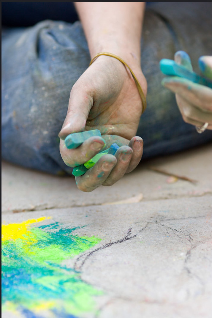 Dana Ellyn blending green and blue pastel chalk into the pavement for the boating party recreation
