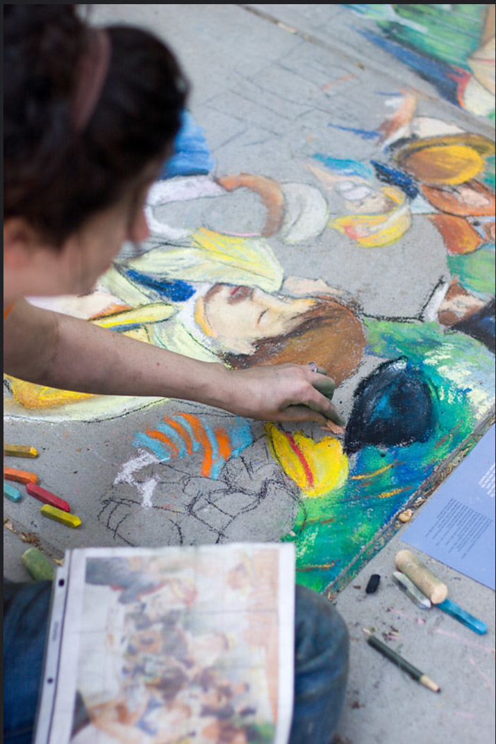 Dana Ellyn leaning in to add detail to a figure's face in the chalk recreation of Luncheon of the Boating Party
