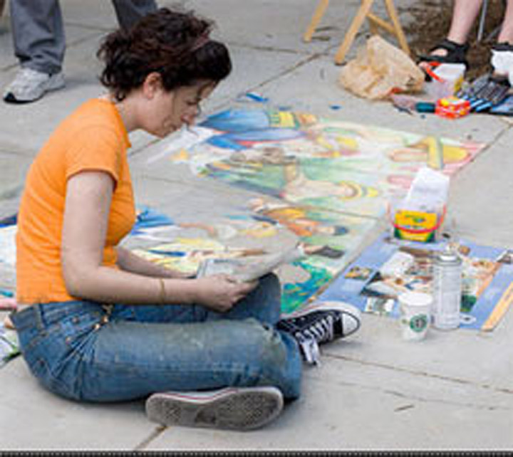 Dana Ellyn sits cross-legged beside the nearly finished chalk recreation of Luncheon of the Boating Party, chalk and supplies scattered around her